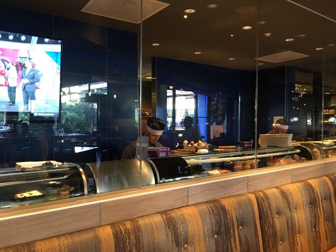 ガラス張りの厨房でスシを握る寿司職人