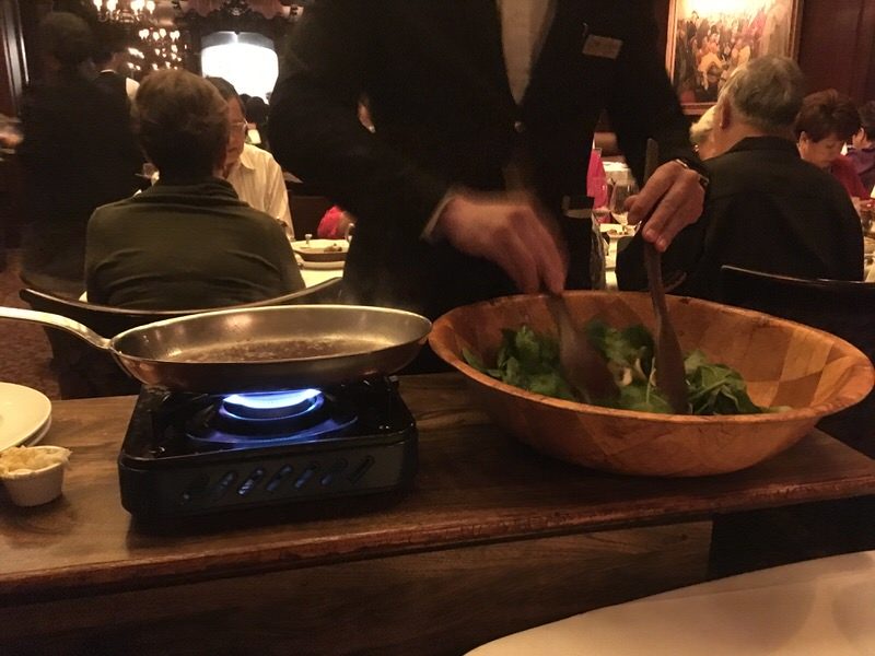 テーブルでサーバーが調理してくれる温かいほうれん草のサラダ